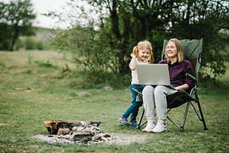 Mother work on Internet with kid outdoors. Quarantine, closed nursery school during coronavirus outbreak. Communication with