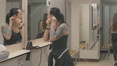 Smiling brunette Caucasian sportswoman getting ready for training in locker room and giving high-five to young lady