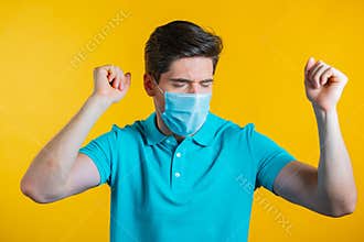 Man in medical mask dancing positive on yellow studio background. Handsome male model guy. Party, happiness, freedom