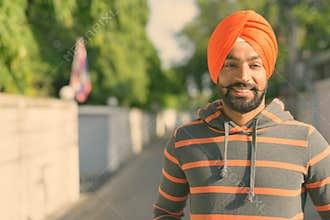 Young handsome Indian Sikh man wearing turban in the streets outdoors