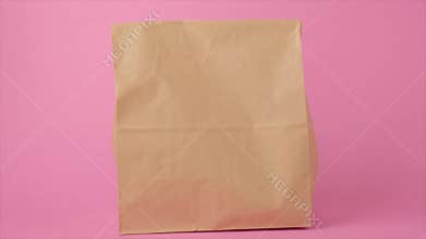 Hand holding brown transparent empty paper takeaway food bag.