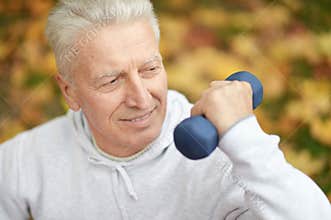 Elderly man exercising with dumbbell in park