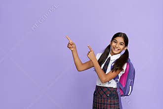 Happy indian school girl pointing advertising isolated on violet background.