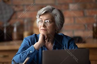 Pensive mature 60s woman look in distance thinking