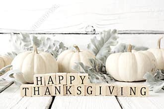 Happy Thanksgiving greeting against white wood with white pumpkins and autumn leaves