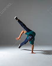 Cool b-boy dancing on one hand in studio  on gray background. Breakdance poster
