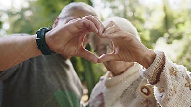 Older retired couple making heart with their hands. Selective focus