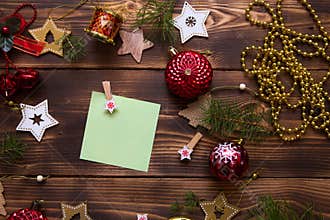 Christmas flat lay of red balloons and wooden stars and clothespins on a dark background with a square sheet for notes in the cent