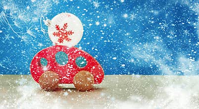 Toy red wooden car carries a Christmas ball. Merry Christmas and New Year holiday background