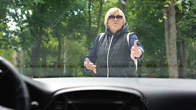 Female pedestrian swearing at car driving in park, traffic rules violation