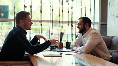 HR manager having job interview with young man in cafe and watching his resume