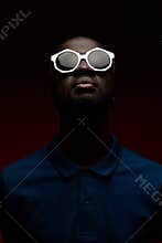Black man face in sunglasses in darkness, studio portrait