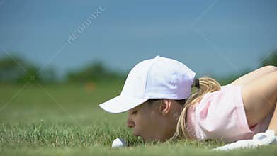 Funny female golf player blowing ball in hole, success strategy and cunning