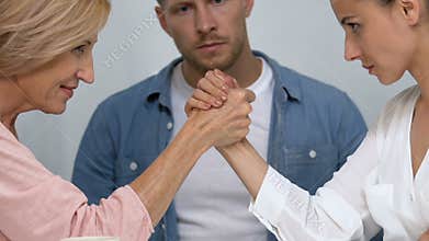 Confused man watching his wife and his mother competing for his attention