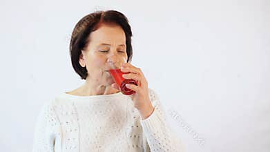 Elderly woman drinking red juice