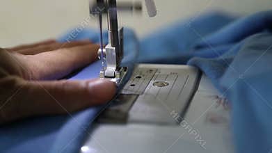 Woman stitching fabric on sewing machine. Hand and sewing process close-up