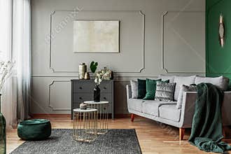 Stylish emerald green and grey living room interior design with abstract painting on the wall