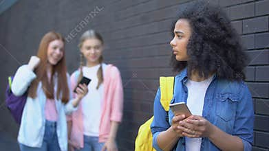 Sad african schoolgirl reading humiliating message, cyber bullying embarrassment