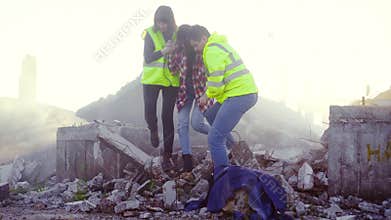 Portrait rescuers in uniform help the victim of the earthquake ,pulling her out from under the ruins of the house