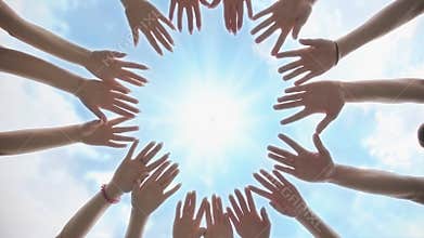 A group of young people make a circle out of their hands. Diverse People Hands Together Partnership.