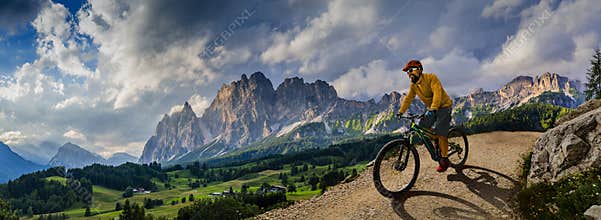 Man cycling on electric bike, rides mountain trail. Man riding on bike in Dolomites mountains landscape. Cycling e-mtb enduro