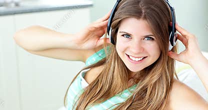 Charming girl listening to music sitting on a sofa