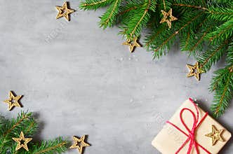Christmas presents with red ribbon on gray background in a frame made of fir branches with star. Flat lay, top view. Christmas