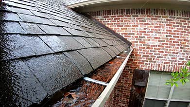 Water overflowing clogged gutter attached to house