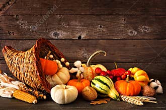 Thanksgiving cornucopia filled with autumn pumpkins and vegetables against dark wood