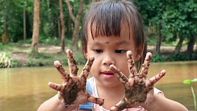 Happy little child girl with dirty hands in summer day.