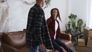 Happy millennial couple owners moved in new home, young family finished relocation unpacking jumping happy on sofa