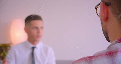 Closeup back view portrait of businessman in eyeglasses talking to his young partner in the office indoors