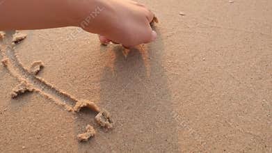 Hand drawing heart shape on sand of the beach.