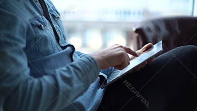 Close-up of a young business man working with a tablet sitting in a chair.