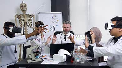 Confident experienced head doctor in white gown lecturing with doctors-interns which using augmented reality glasses and