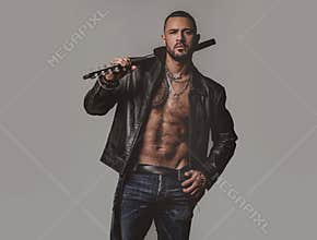 Brutal attractive bearded biker man with tattooed poses in black jacket. Copy space. Handsome bearded man. Serious