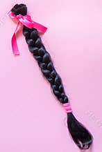 Brown hair braid on pink background for hair donation for women with cancer chemotherapy