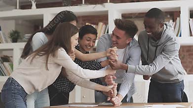 Happy young diverse business people making fists pyramid.