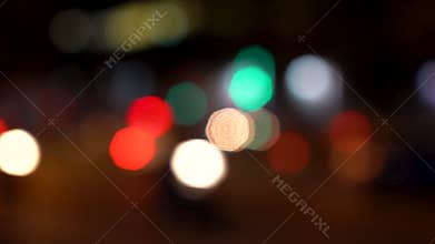 Defocused or soft focus bokeh lights of cars, scooters, motorbikes and traffic driving on city streets at night