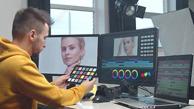 Freelance videographer colorist editing footage using professional software, monitor and montage console.