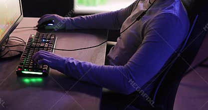 Unrecognizable man gamer playing computer game sitting at table, side view.