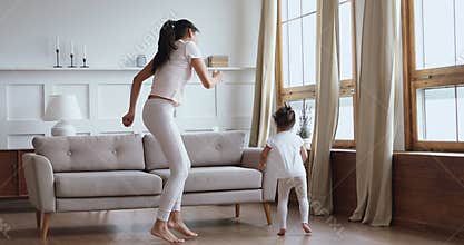 Carefree healthy mom and child daughter having fun dancing together