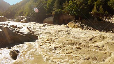 holy river Ganges rocky channel high mountains Himalaya with coniferous forest sun shines in blue sky violent stream of water