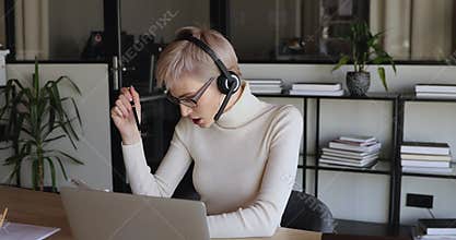 Smiling female office worker wearing headset communicating by video call