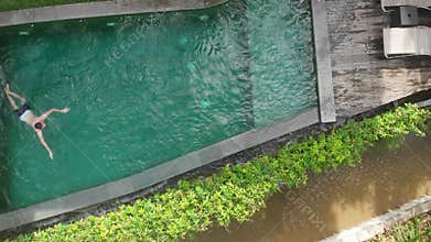 Aerial Top Down View of man swimming in luxury pool in jungle in Ubud Bali.Vacation concept.