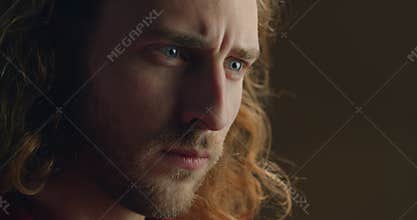 Close up view of young handsome mans face creating art object. Millennial guy with long hair and blue eyes working