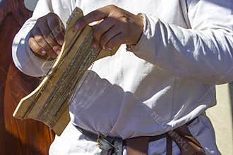 Man in national costume is making bowstring for  bow,  master class on craft