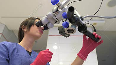 Dentist using dental microscope in dentistry for operation of a woman patient