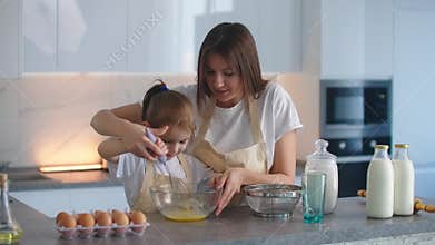 Mom and daughter whisk together a dough for bread or a family cake. Mom shares her secrets with her daughter teaching