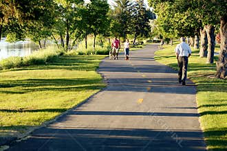 Indivuals and couples walk on a city maintained green way trail.
